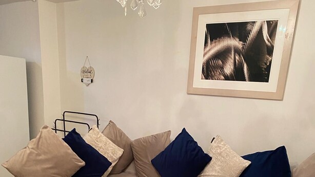 Een moderne woonkamer met een beige modulaire bank, een witte salontafel en een kroonluchter.