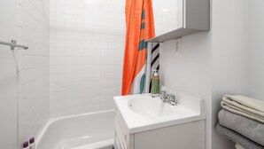 Un baño con una bañera blanca, un lavabo y un perchero para toallas.