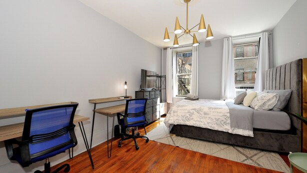 Un dormitorio con cama, escritorio, sillas y televisor.