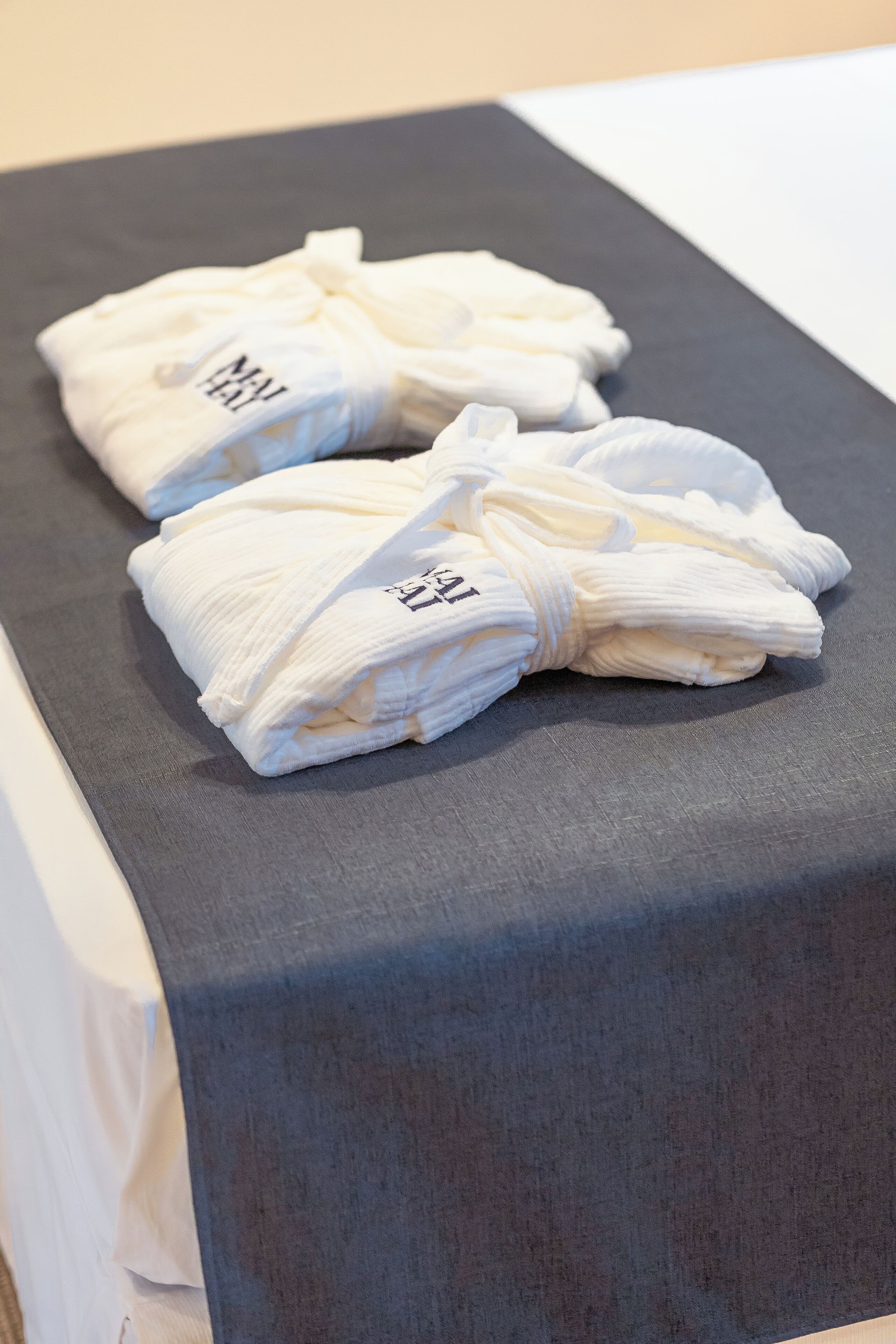 A neatly folded white towel with a logo on a gray surface.