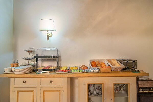 A breakfast buffet setup with a coffee maker, toaster, and various food items on a wooden counter. - Corte dell'albero (Florence)