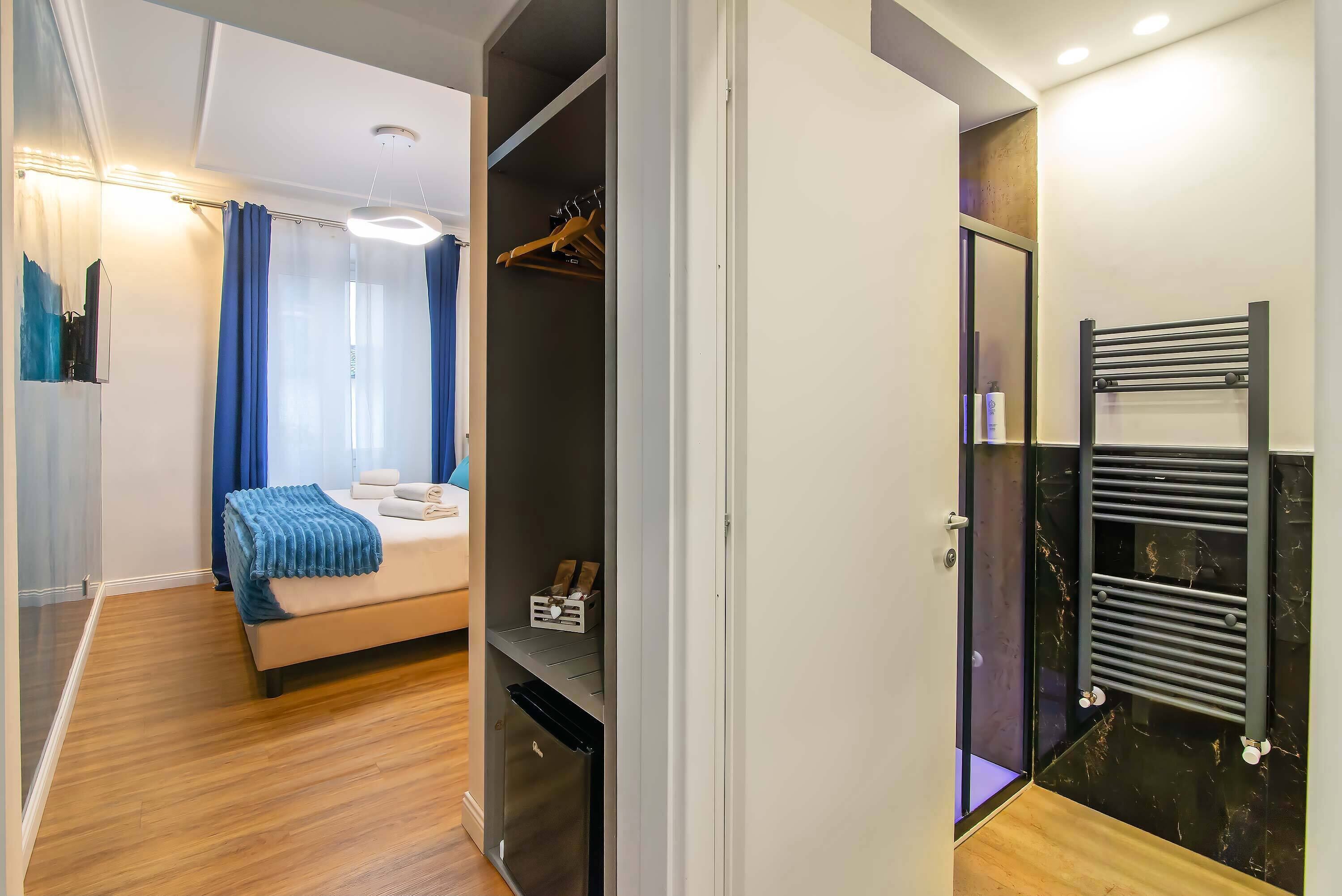A bedroom with a bed, a wardrobe, and a bathroom with a towel rack.