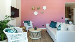 Ein modernes Wohnzimmer mit rosafarbener Wand, weißen Möbeln und Wanddekoration.