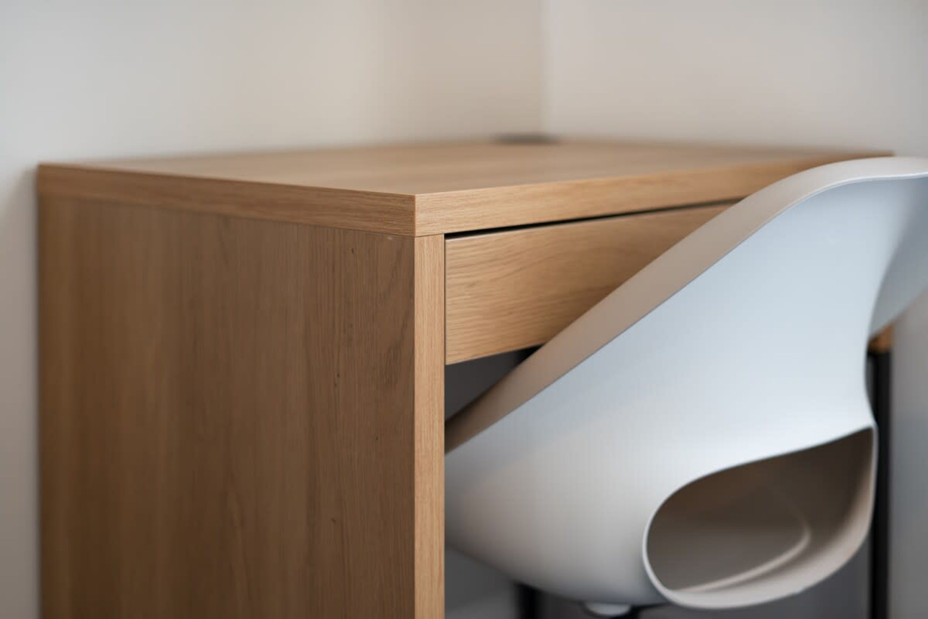 A corner of a room with a wooden cabinet and a white chair.