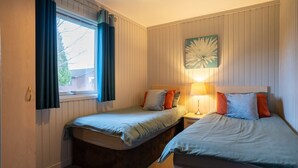 A bedroom with two beds, a window with curtains, a wall clock, and a bedside lamp. - 3 Bedroom Lodge - Hunters Quay (Dunoon)