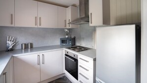 A modern kitchen with white cabinets, a stainless steel range hood, a microwave, and a refrigerator. - 3 Bedroom Lodge - Hunters Quay (Dunoon)