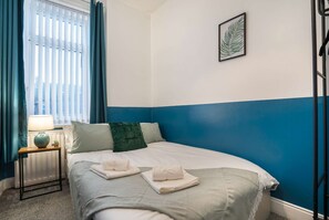 A bedroom with a bed, a nightstand, a lamp, a window with curtains, and a wall-mounted picture. - 3 Bed-free Parking-close to City (Gateshead)