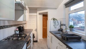 A modern kitchen with a gas stove, white cabinets, a window with a view, and a potted plant. - 3 Bed-free Parking-close to City (Gateshead)