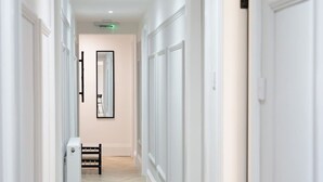 Un couloir aux murs blancs, doté d’un parquet en point de Hongrie et agrémenté d’un banc.