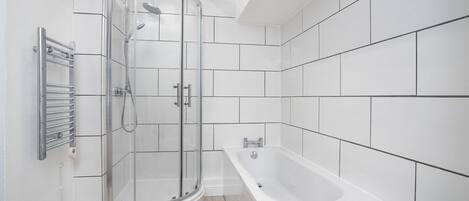 Une salle de bain moderne avec une douche à parois de verre, une baignoire sur pied et des murs recouverts de carreaux blancs.