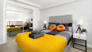 Une chambre moderne avec un grand lit, une table de chevet avec une lampe et un miroir.