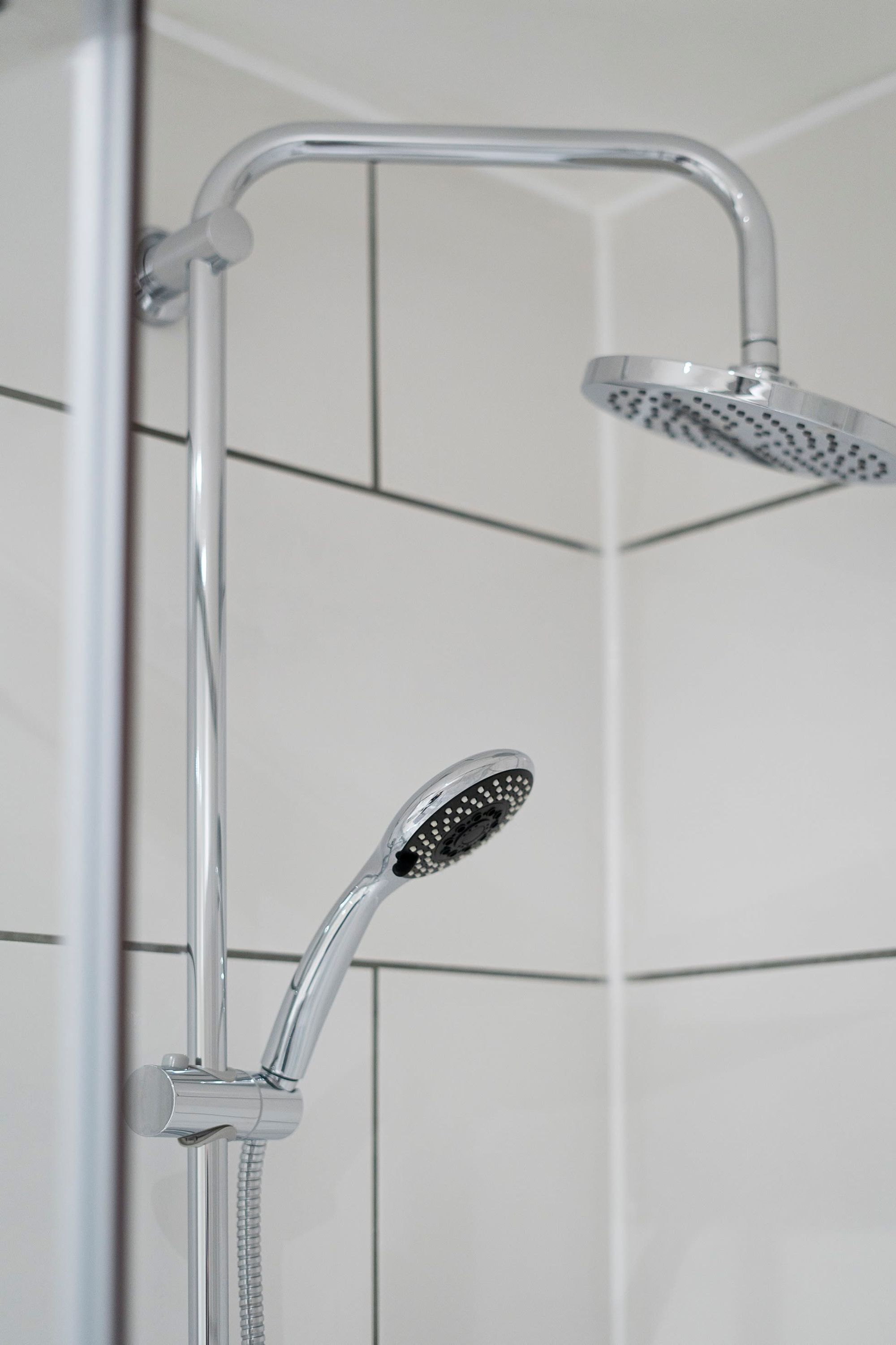 A shower with a handheld showerhead and a fixed overhead showerhead.