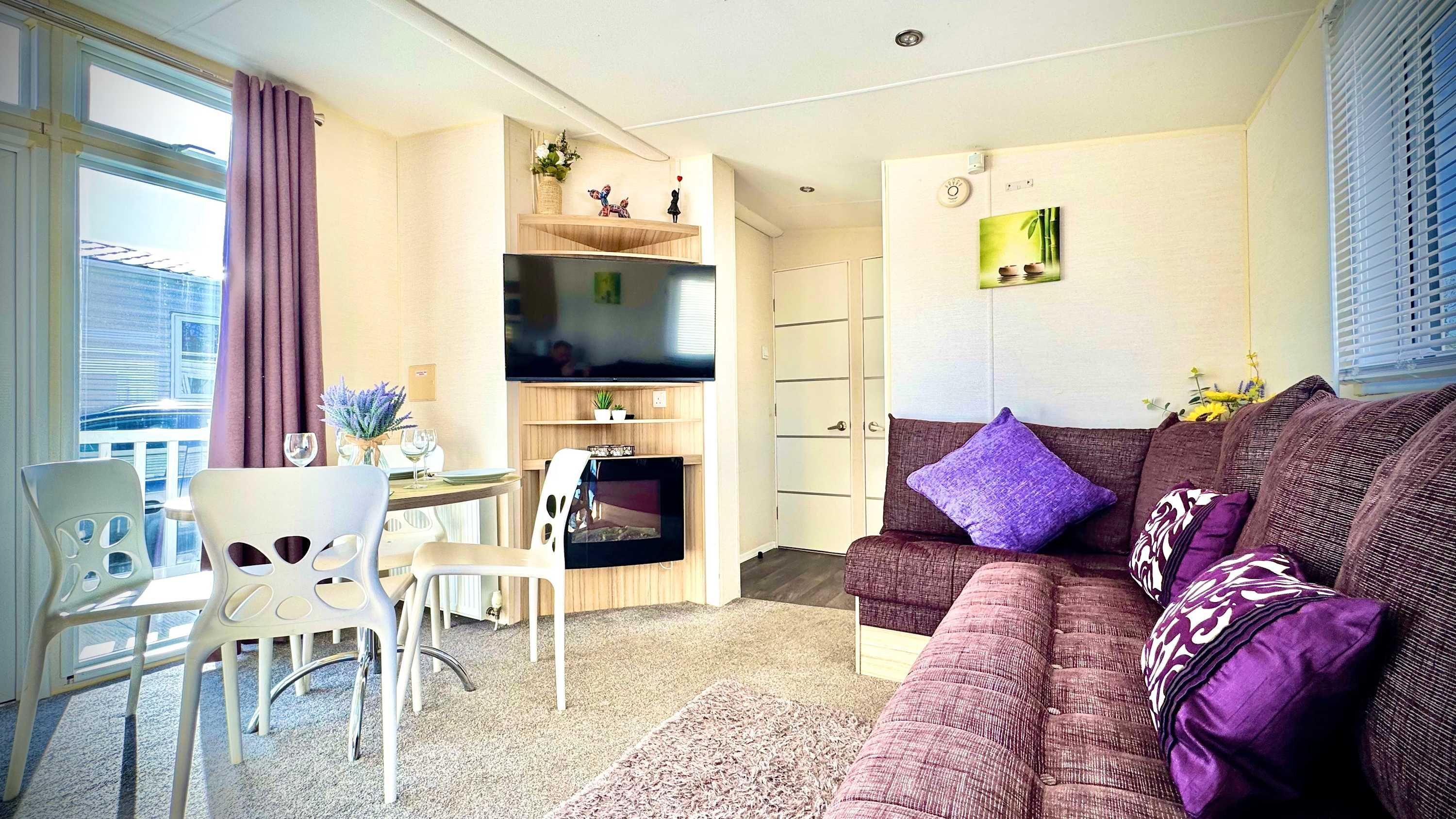 A compact living space with a sofa, a dining table, and a TV mounted on the wall.