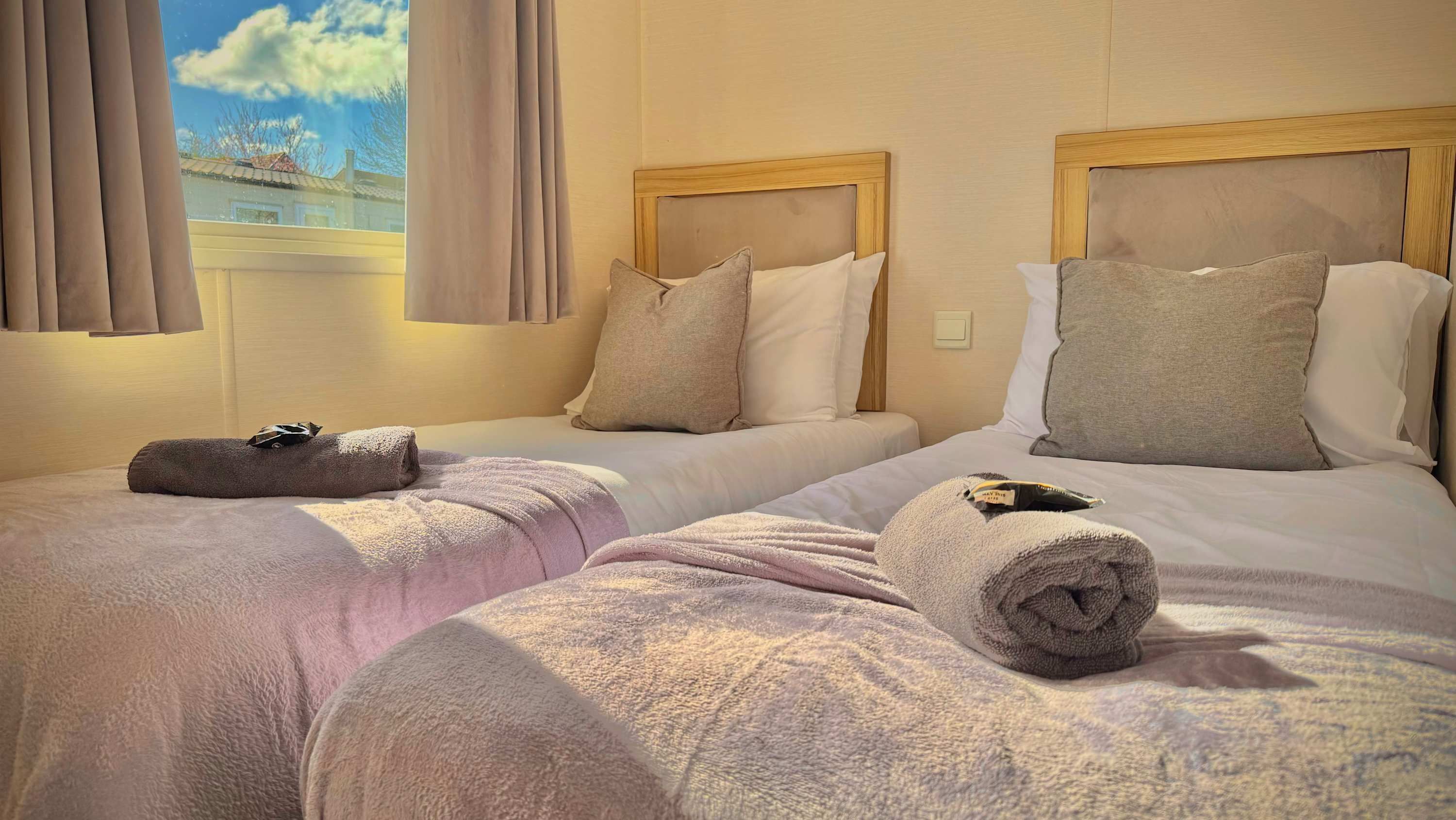 Ein Hotelzimmer mit zwei Betten, jeweils mit Kopfteil, Kissen und Handtüchern.