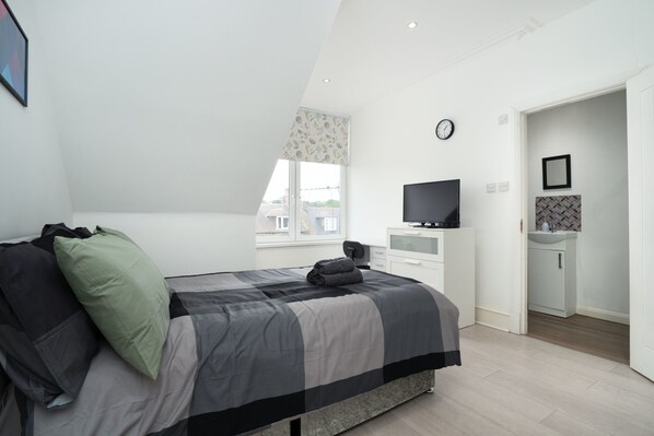 A modern bedroom with a bed, a TV, a small bathroom, and a window with a view. - Cosy Fully Equipped Studio 6 Close to University (Aberdeen)