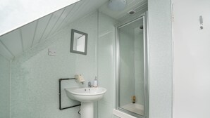 A bathroom with a white pedestal sink, a mirror, and a glass-enclosed shower. - Cosy Fully Equipped Studio 5 Close to University (Aberdeen)