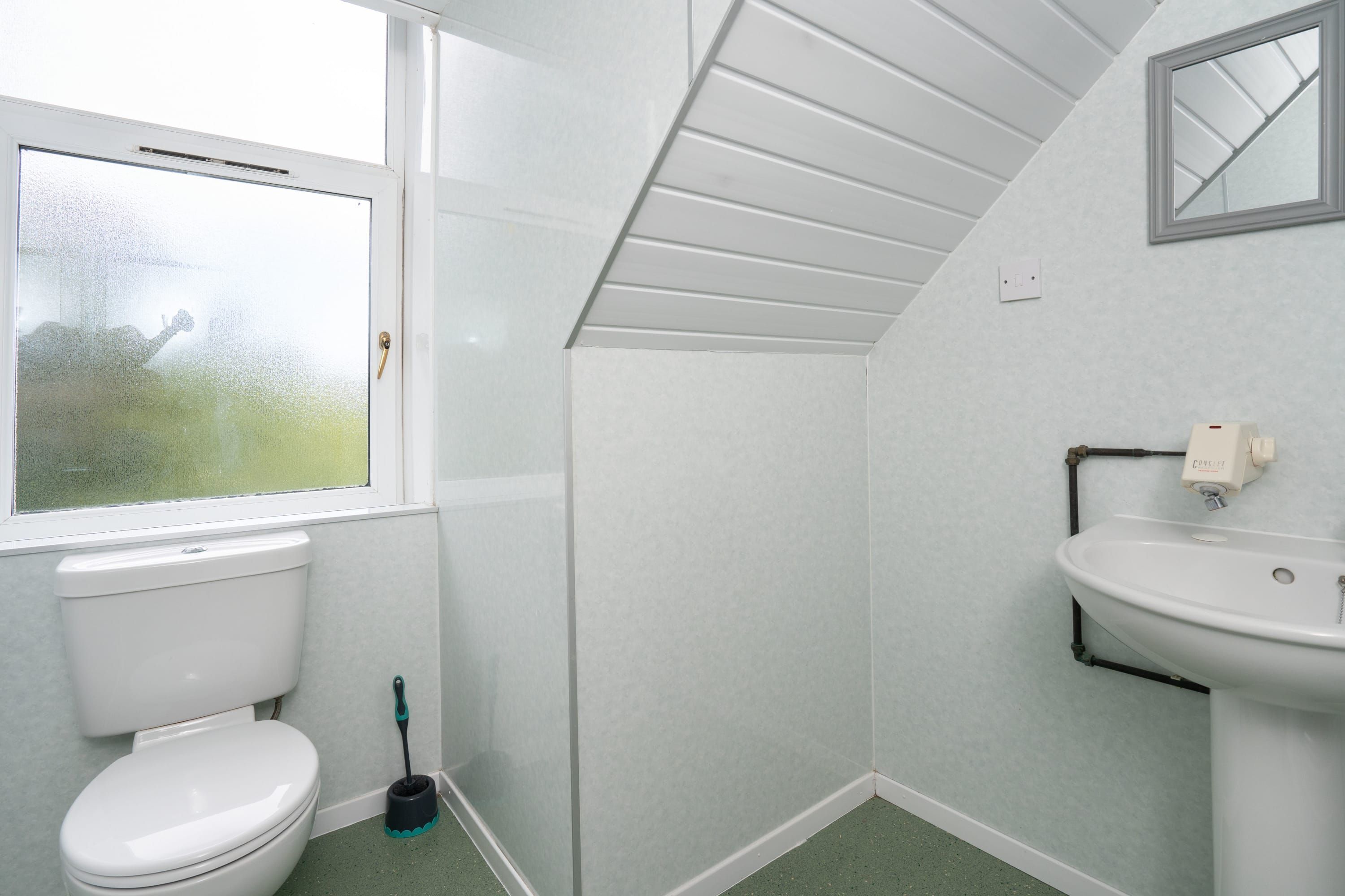 Ein Badezimmer mit Toilette, Waschbecken, Fenster und Spiegel.