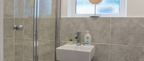 A bathroom with a glass shower enclosure, a pedestal sink, and a toilet.
