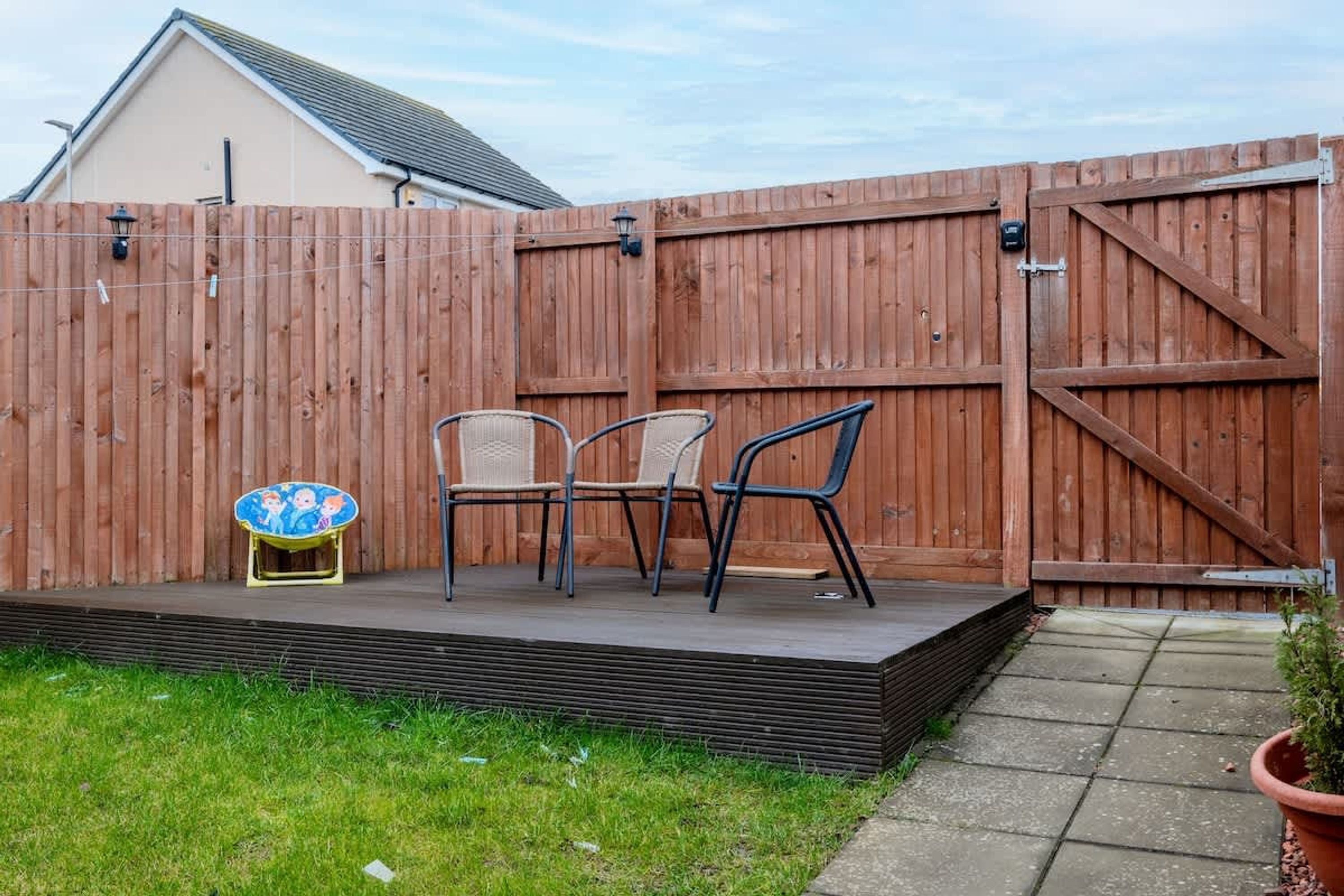 A wooden deck with chairs and a small table, surrounded by a wooden fence.