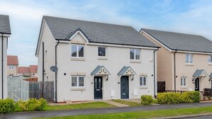 A row of two-story houses with pitched roofs, white exteriors, and dark-colored doors. - 3 Bedroom House-private Parking (Bonnyrigg)