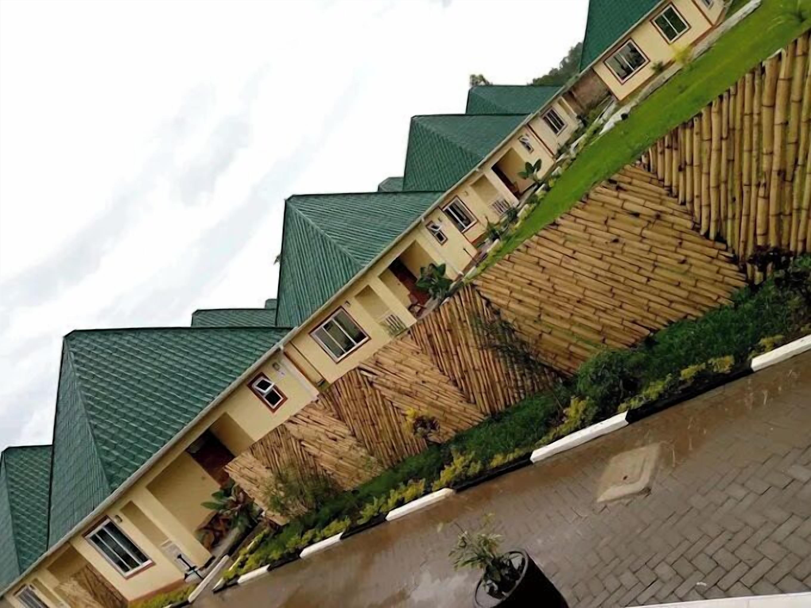 Un edificio residenziale con diversi piani, tetti verdi e una recinzione in bambù.