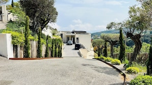 A modern house with a gravel driveway, surrounded by greenery and trees. - Architect-designed house with sea and mountain views (Bastia)