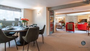 A dining area with a round table set for four, a sofa, and a fireplace in the background. - Bay Tree Cottage - Three Bedroom Cottage, Sleeps 5 (Burton Bradstock)