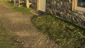 Filas de casas de piedra con un camino de grava frente a ellas, ubicadas en una ladera.