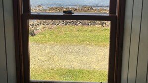 Una ventana con vista a una costa rocosa y un acantilado.