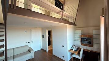 A spacious loft with a high ceiling, a staircase, a sofa, a dining area, and a kitchen.