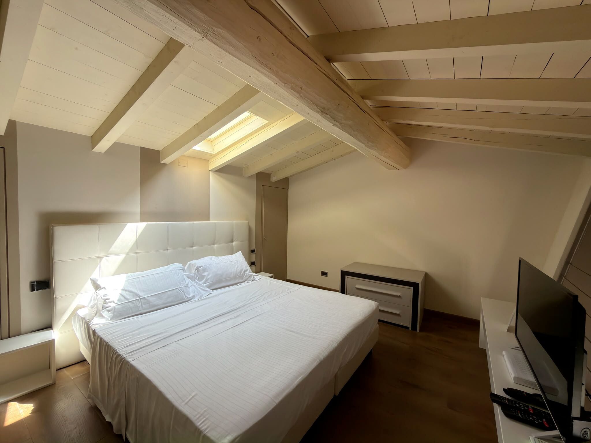 Una camera da letto con un letto grande, una televisione e una scrivania con un computer.
