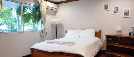 A neatly made bed with white linens, a wooden headboard, and a bedside table with a lamp.