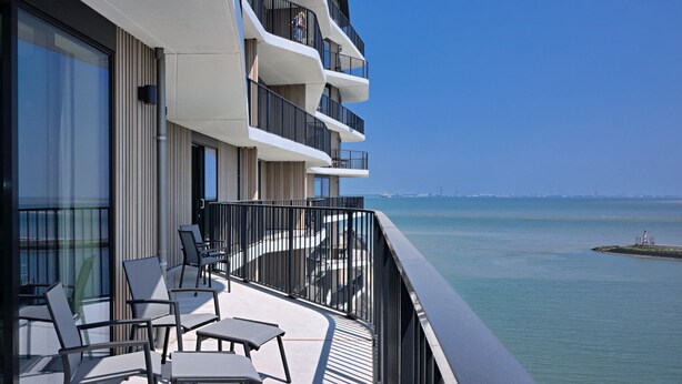Un balcón moderno de hotel con varios niveles, con vistas al mar.