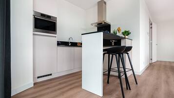 A modern kitchen with a built-in oven, a sink, and two black bar stools.
