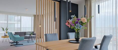 Un comedor moderno con una mesa de madera, sillas tapizadas de gris y un jarrón con flores.