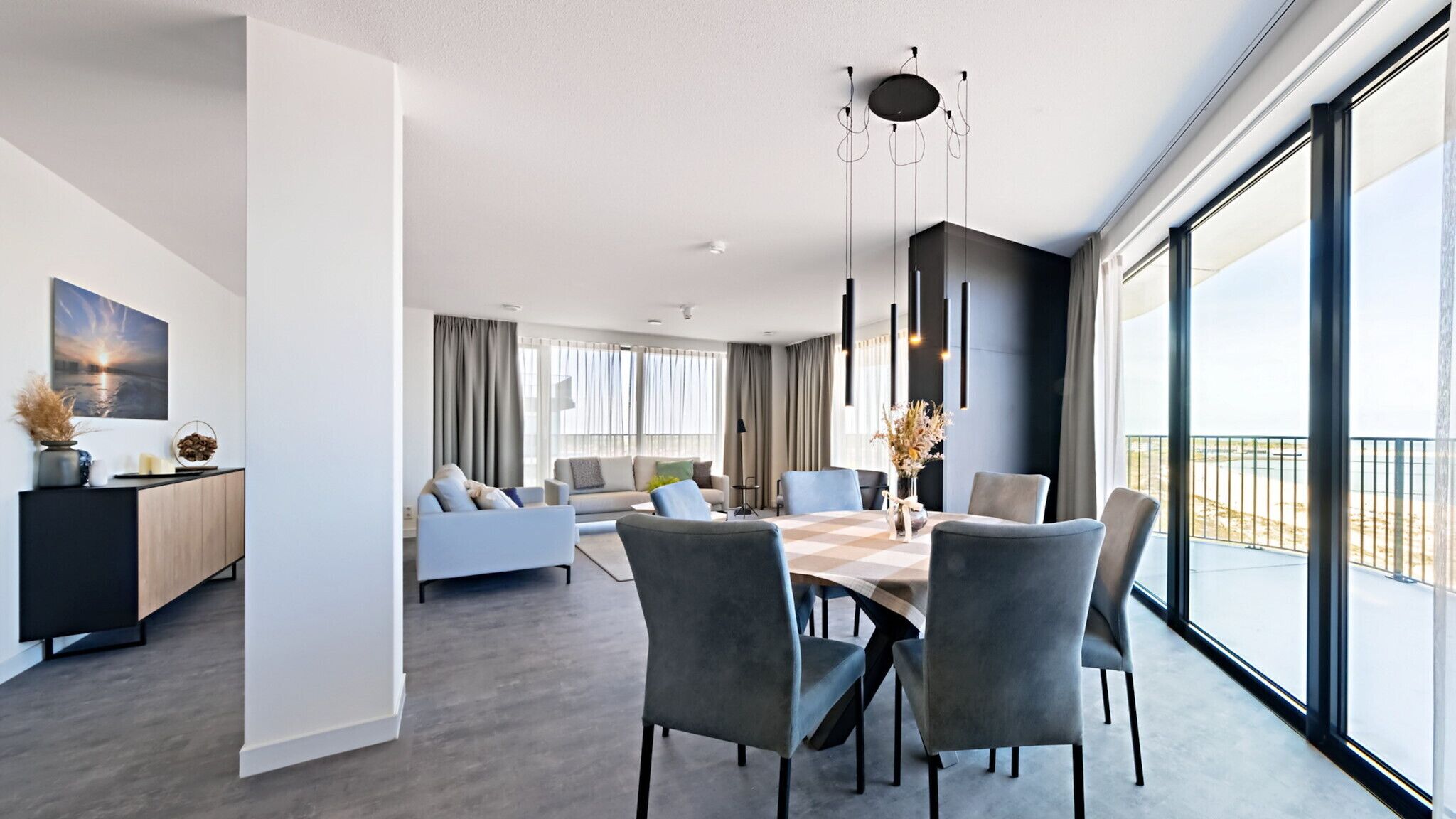 A modern living room with a dining area, large windows, and a view of the outdoors.