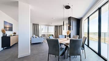 A modern living room with a dining area, large windows, and a view of the outdoors.