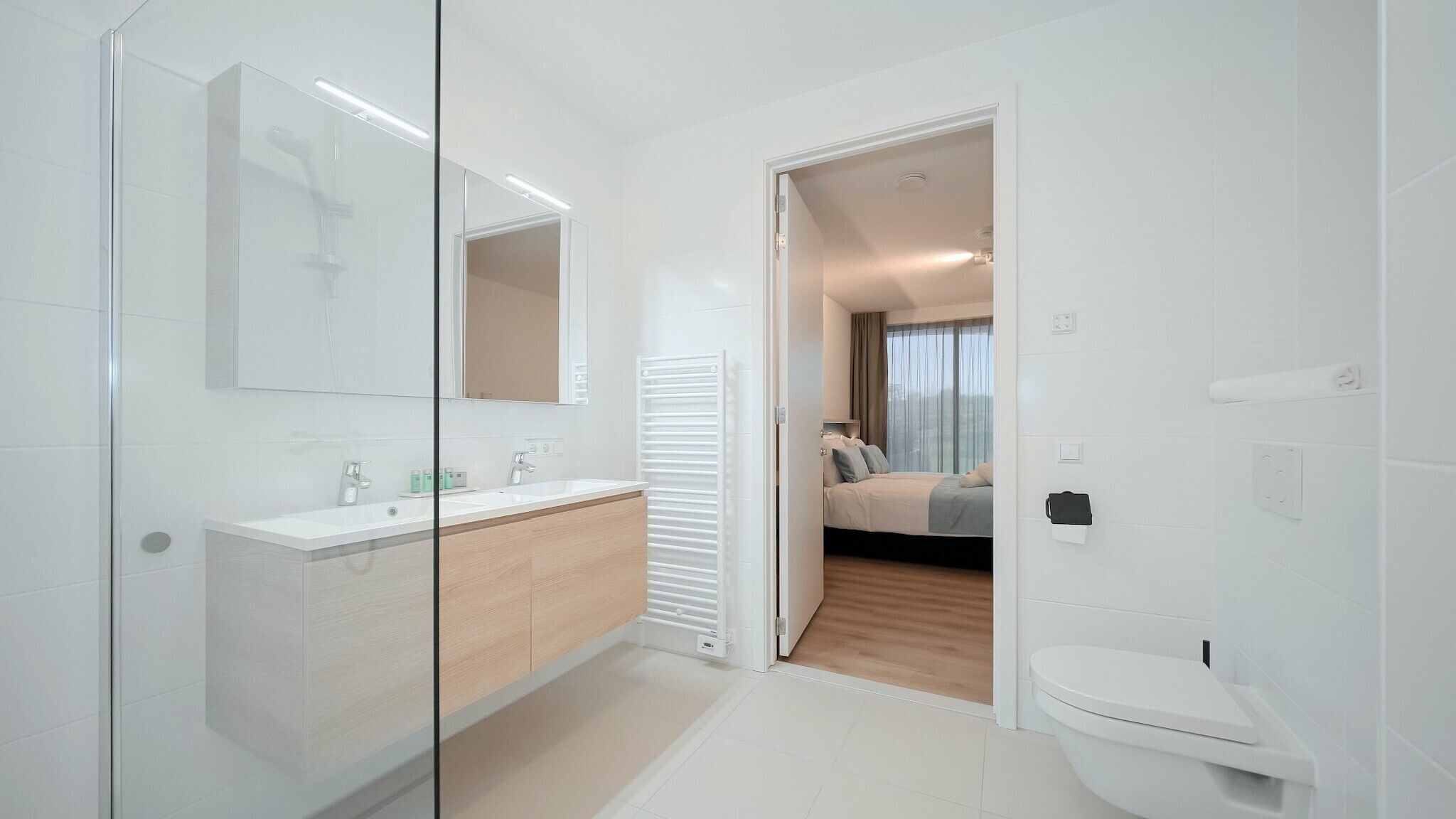 Een moderne badkamer met een douchecabine van glas, een wit wastafelmeubel en een toilet.