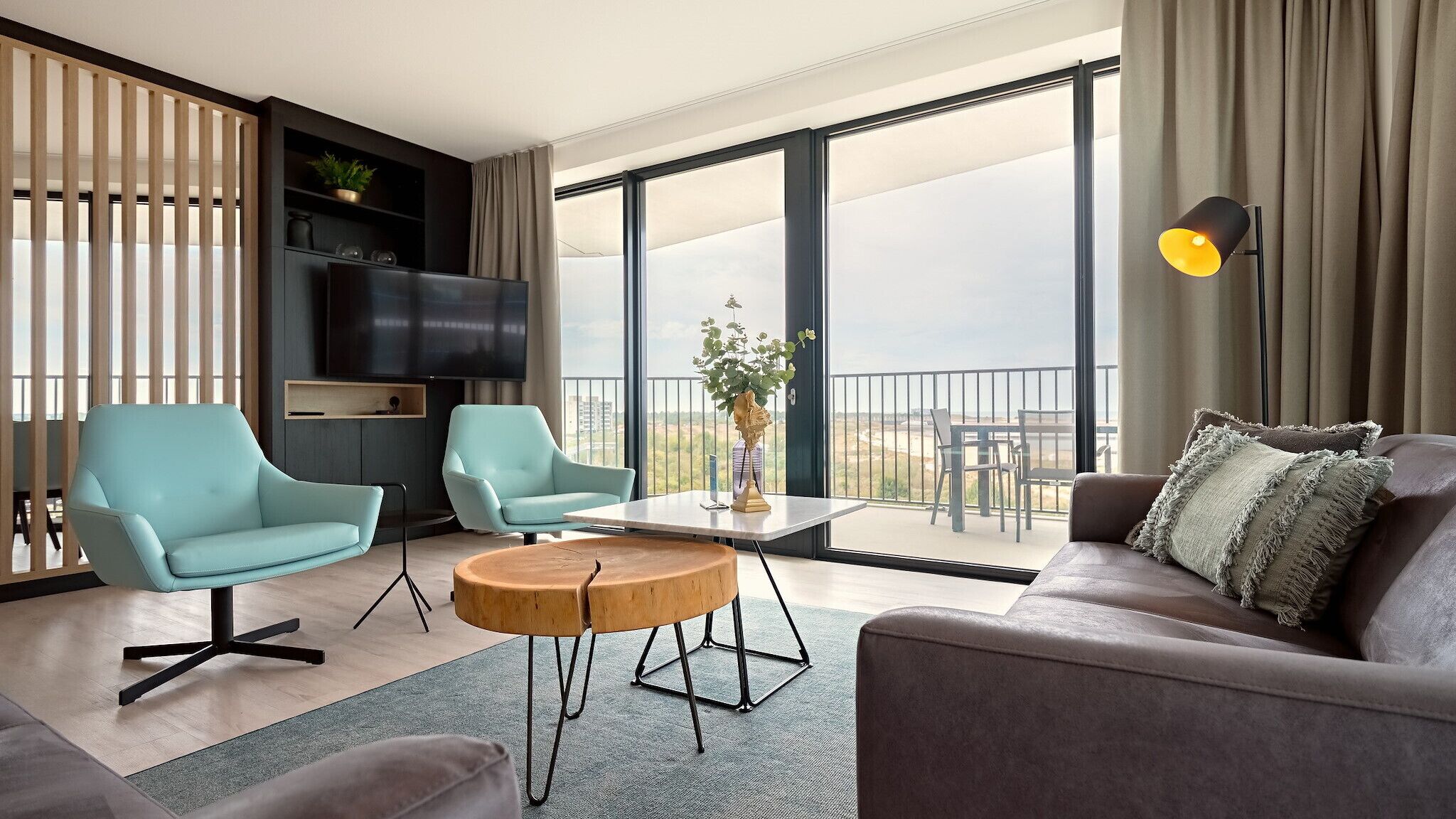 Una sala de estar moderna con un sofá, dos sillones, una mesa de centro y un televisor en la pared.
