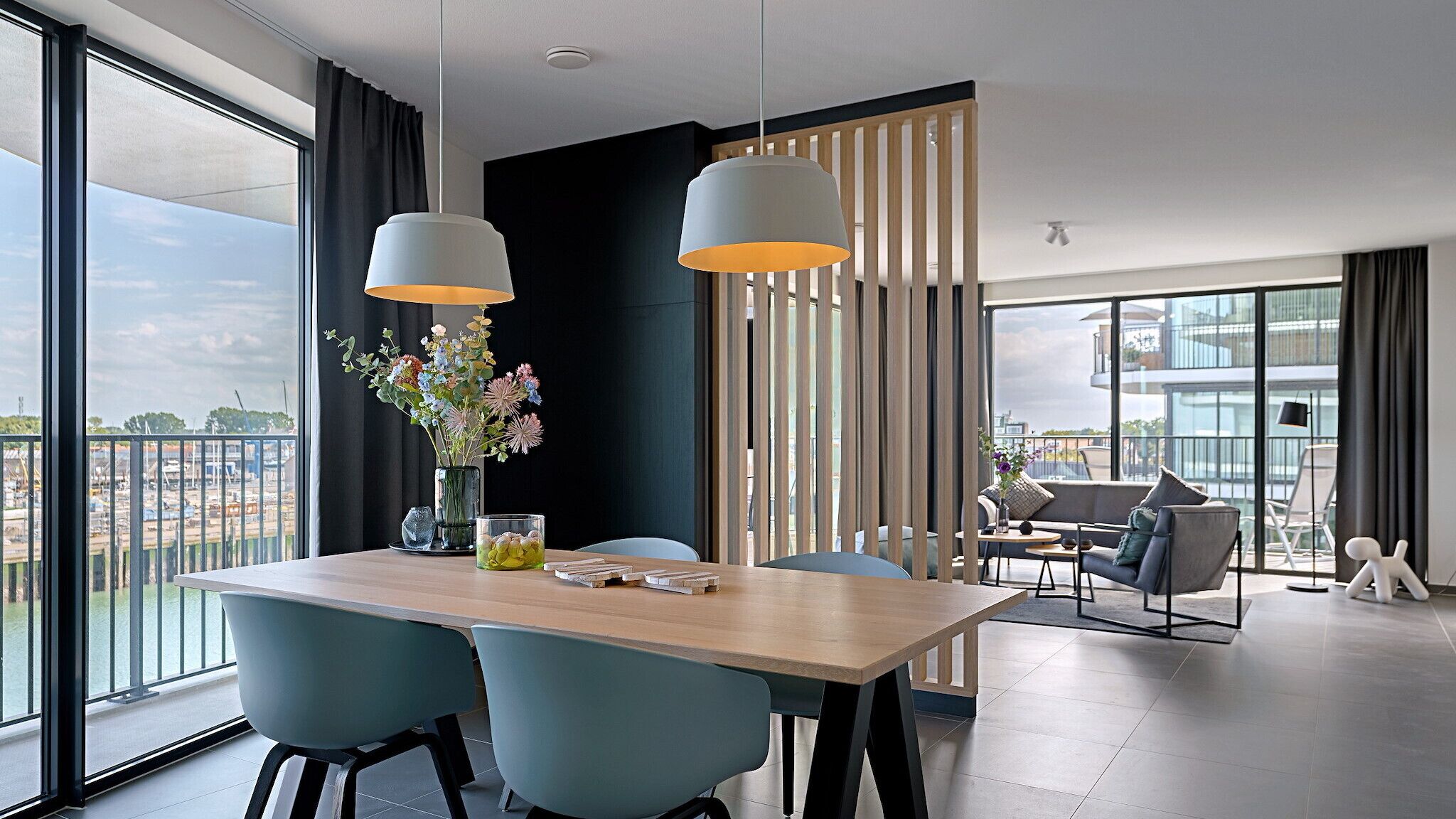 Uma sala de jantar moderna com uma mesa de madeira, duas cadeiras azuis e um vaso de flores.