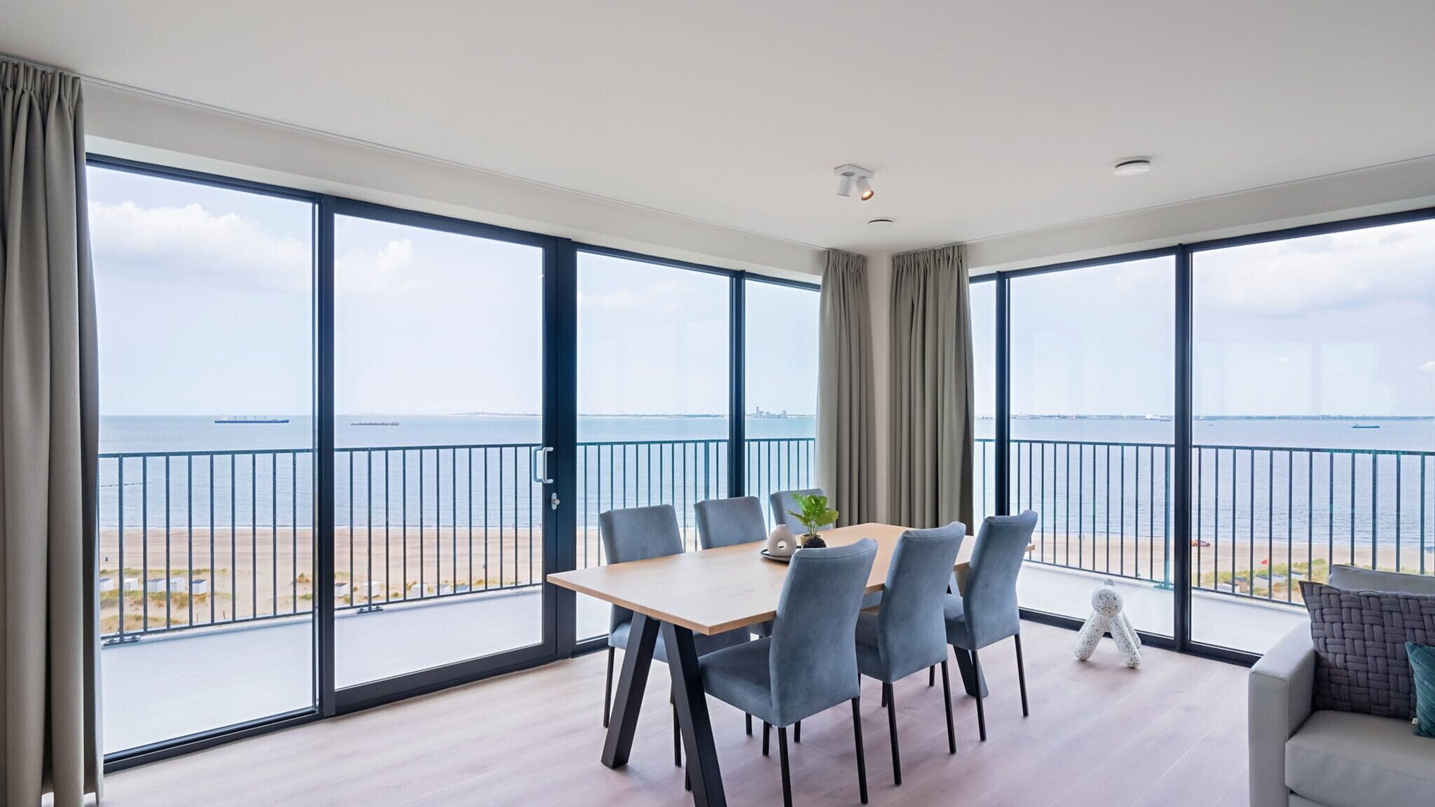 Een ruim balkon met uitzicht op zee en een stadsbeeld.