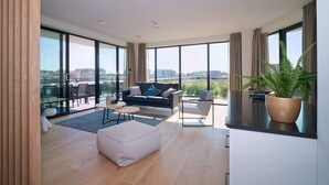 Un salón amplio con un ventanal grande, un sofá, una mesa de centro y una planta en maceta.