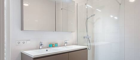 Un baño moderno con un espejo grande, un lavabo y una ducha con cerramiento de vidrio.