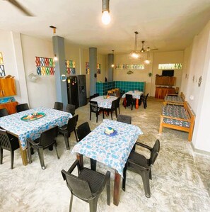 A dining area with tables and chairs, a refrigerator, and a television. - Apartasuite steps from the beach - Coveñas (Coveñas)