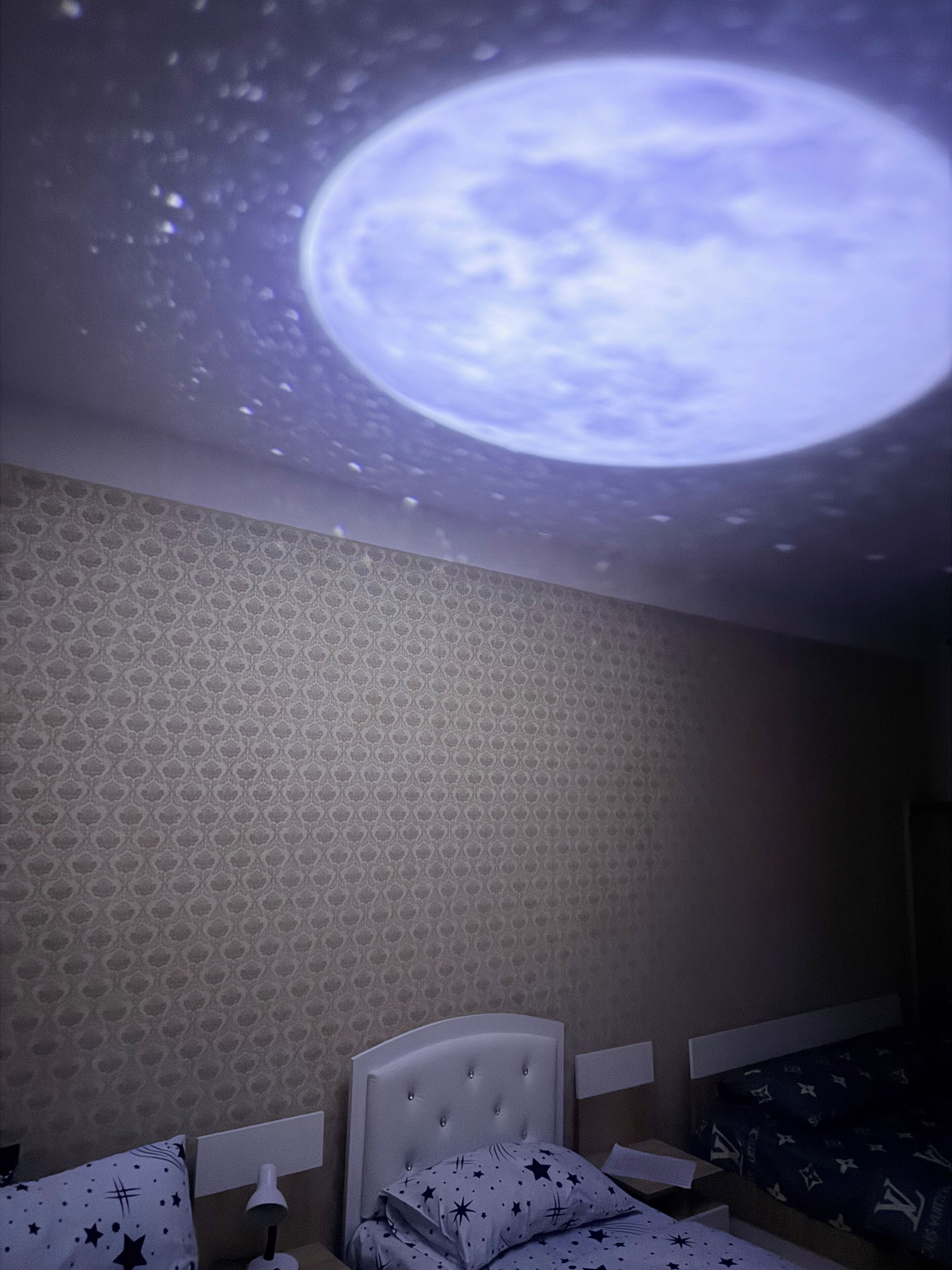A bedroom with a bed, a nightstand, and a wall with a patterned wallpaper.