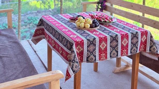 A covered outdoor seating area with a table set for a meal, surrounded by a scenic view of greenery and mountains. - JIV Guesthouse in Odzun (Odzun)