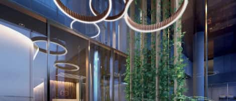 Eine moderne Lobby mit Glastrennwänden, einer vertikalen Grünwand und runden Leuchten.