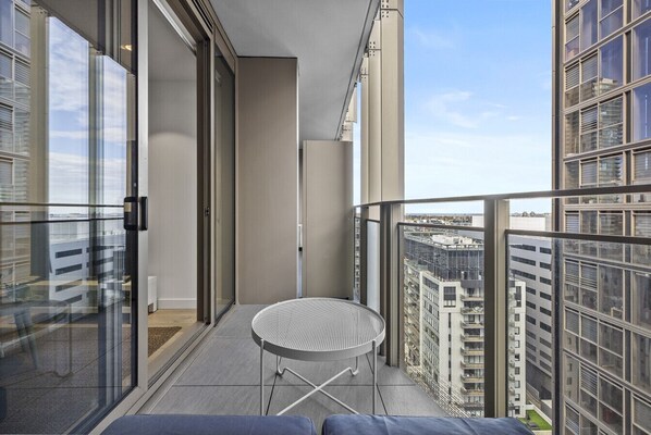 Ein Balkon mit rundem Tisch, Glastüren und Blick auf die Stadt.