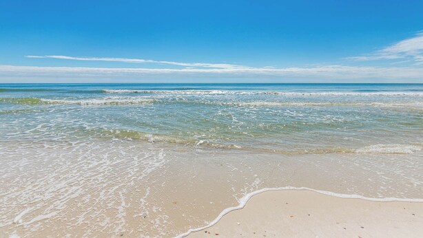 A beach with clear blue water and a sandy shore.