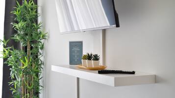 Una habitación moderna con un escritorio blanco, una planta en maceta, un control remoto y un cartel que dice 'home's share'.